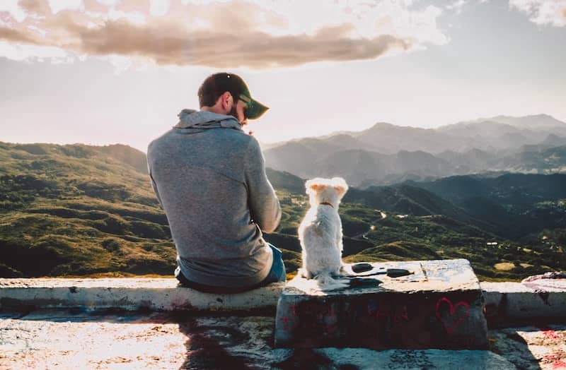 Young guy sitting with his dog enjoying the view - slow living at its best!