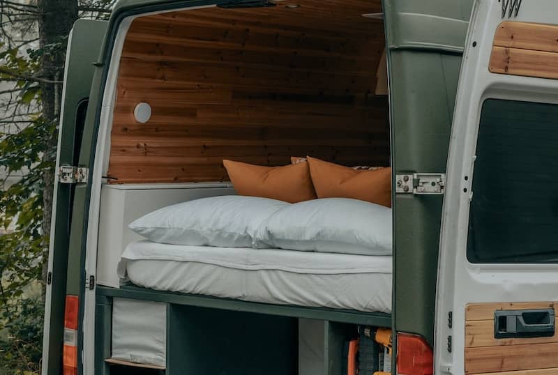 View into back of a van with thick mattresses and cozy wedding