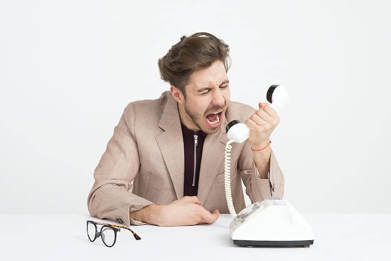 Angry man shouting at phone on a white background