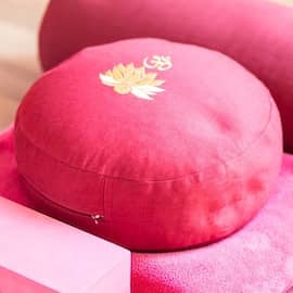 Close-up of pink yoga cushion with a golden logo embroidered on it.